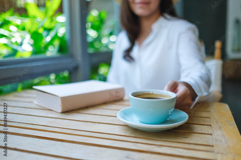 Closeup image of a woman drinking coffee with a book on table Closeup image of a woman drinking coffee with a book on table