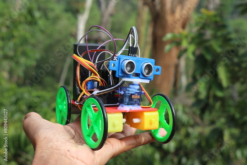 Holding a programmable robotic car that is capable of avoiding obstacles in is path and change the direction of movement using sensors and servo
