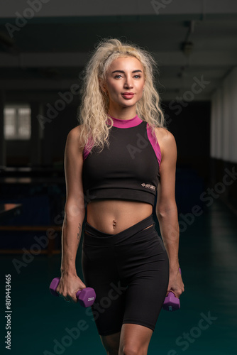 Portrait of a young beautiful blonde girl in a sports uniform in the gym.