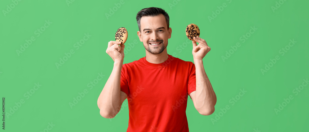 Fototapeta premium Handsome man with tasty cookies on green background