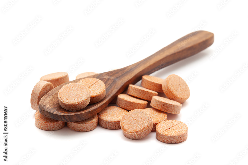 Health care concept. A wooden spoon filled with Orange Medical Pills and Tablets. Isolated on a white background. Health care concept. A wooden spoon filled with Orange Medical Pills and Tablets. Isolated on a white background.