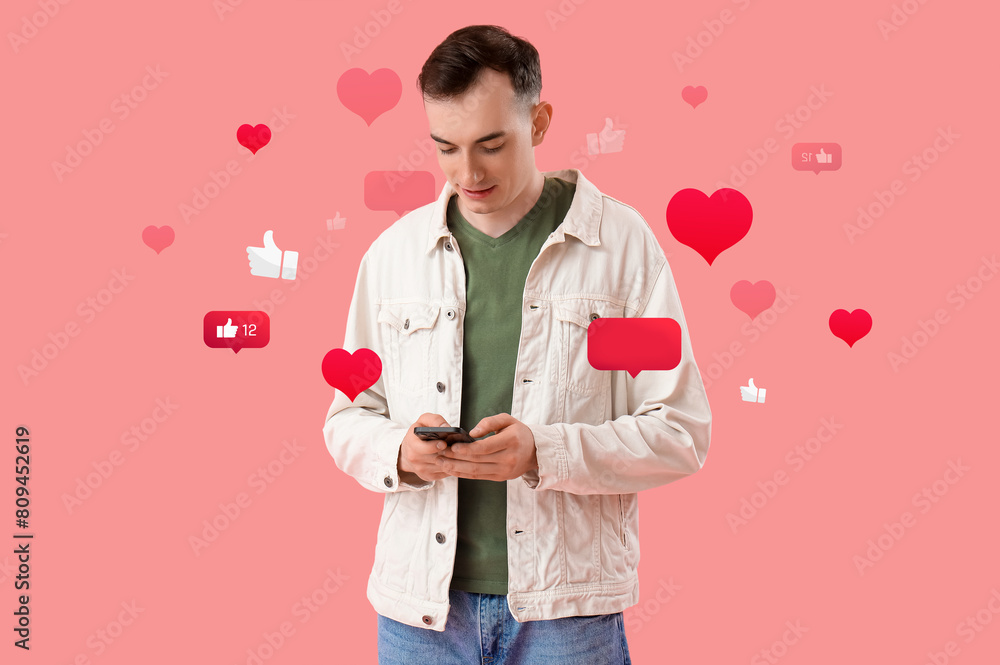 Young man with mobile phone messaging on pink background Young man with mobile phone messaging on pink background