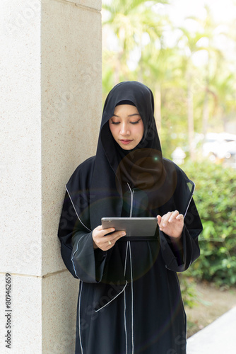 Photography Young Asian beautiful woman Muslim student portrait in traditional clothes relaxing and hold tablet in school building