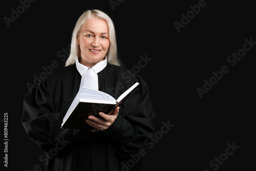 Mature female judge with book on black background