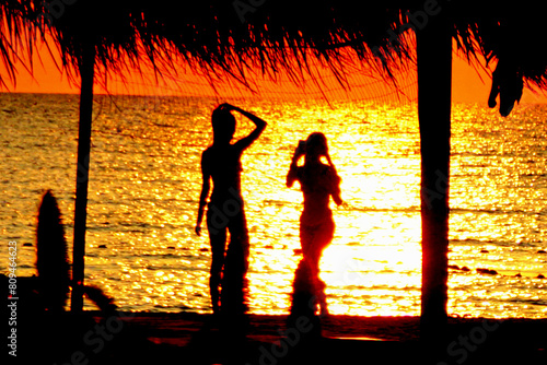 Silhouette of young women relax on beach with sun reflection on sea surf, Beautiful summer