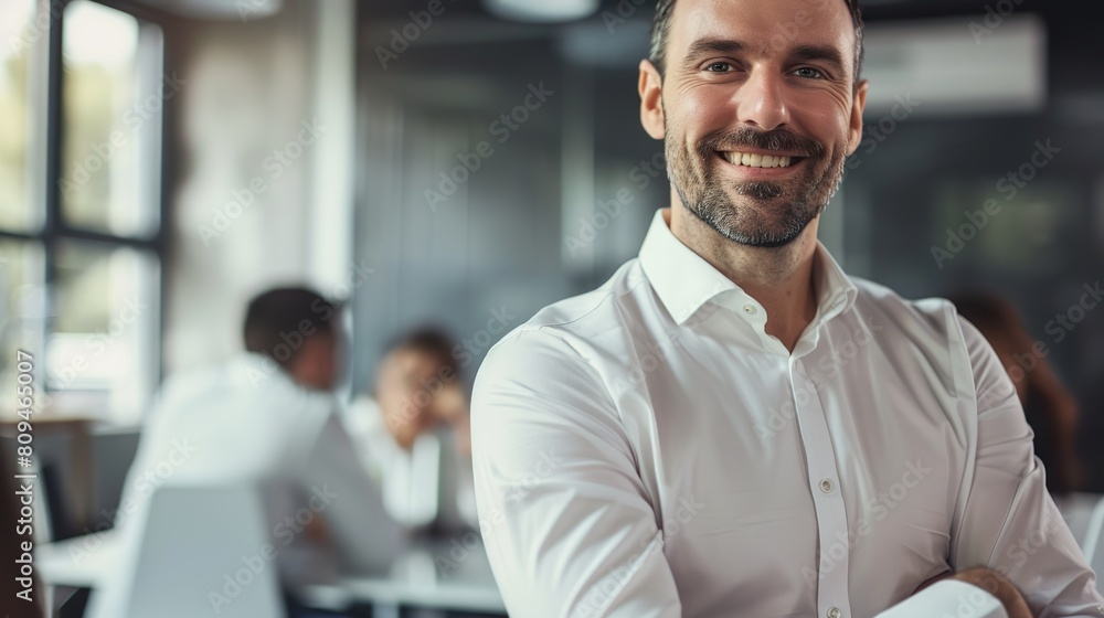 Handsome businessman in casual clothes smiling and looking at camera while standing in office Handsome businessman in casual clothes smiling and looking at camera while standing in office