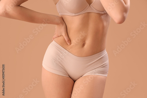 Beautiful young woman in stylish beige underwear on brown background, closeup © Pixel-Shot