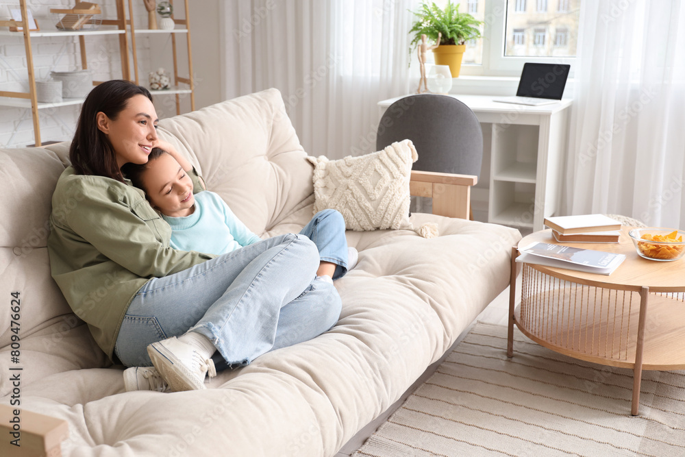 Happy mother with her little daughter watching TV on sofa at home Happy mother with her little daughter watching TV on sofa at home