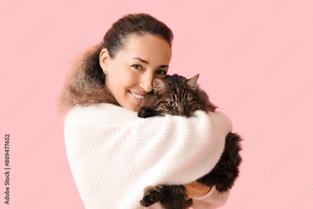 Beautiful mature woman with cute cat on pink background