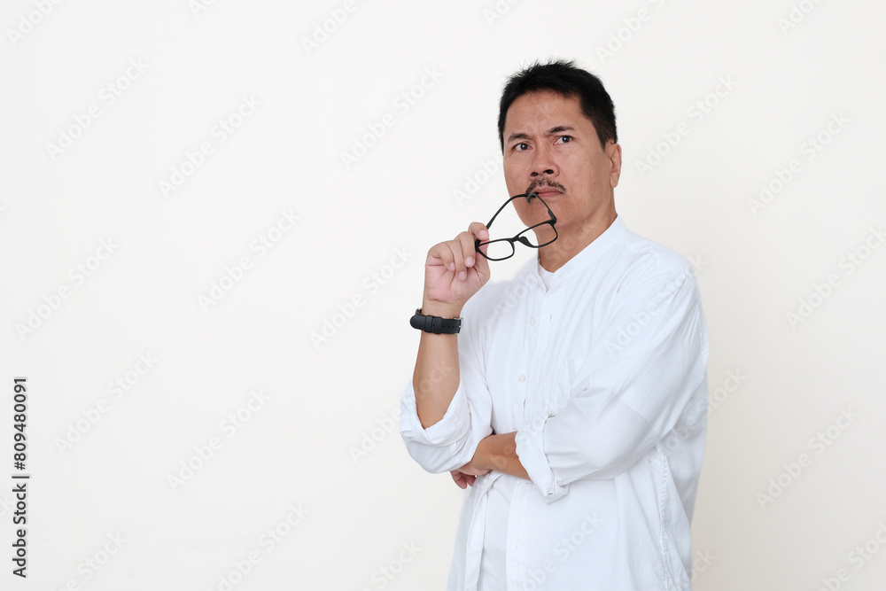 Man standing alone biting his glasses frame looking very insecure Man standing alone biting his glasses frame looking very insecure