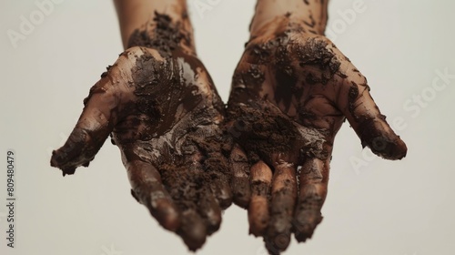 A pair of hands covered in mud and grime  sharply focused against a pristine white background