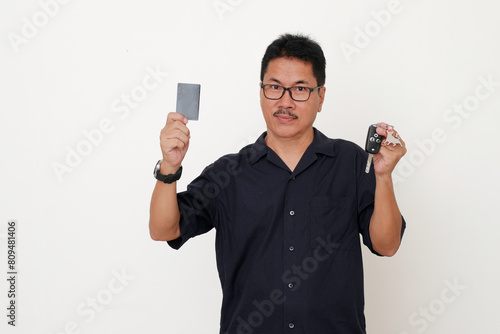 Man standing with confident facial expression, while both hands showing membership card and car key photo