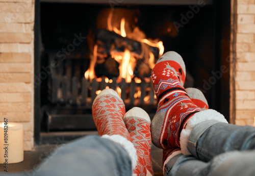 Couple, Christmas and socks by fireplace for celebration to relax at house, romantic and bonding on holiday in winter. People, legs and warm for home, together and love for comfort, wool and heat