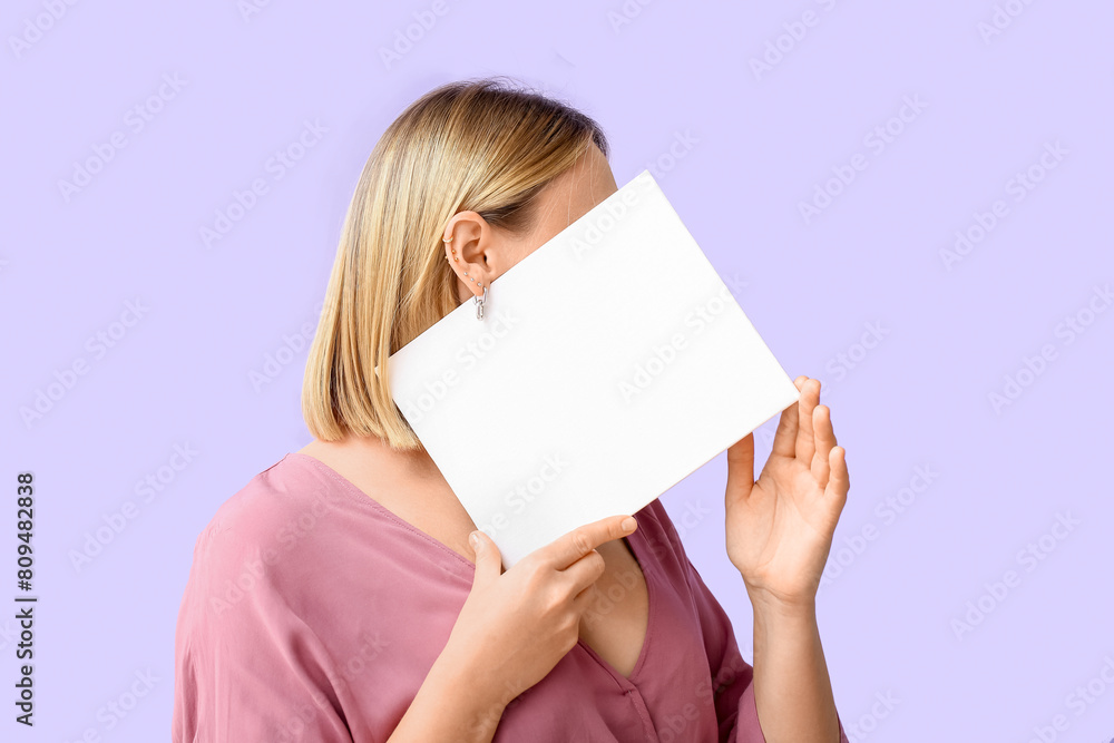 Woman with multiple ear piercing and blank paper sheet on lilac background Woman with multiple ear piercing and blank paper sheet on lilac background