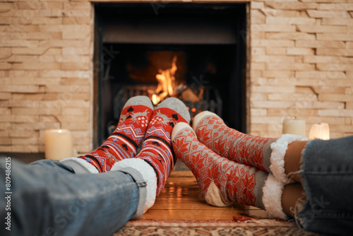 Christmas  socks and couple by fireplace for celebration to relax at house  romantic and bonding on holiday in winter. People  legs and warm for new year  together and love for comfort  wool and heat