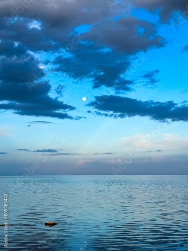 Moon over the lake. Full moon in the clouds. Kyrgyzstan, Lake Issyk-Kul