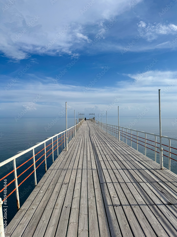 Wooden pier on the seashore. Mountains and clear water. Lake Issyk-Kul, Kyrgyzstan