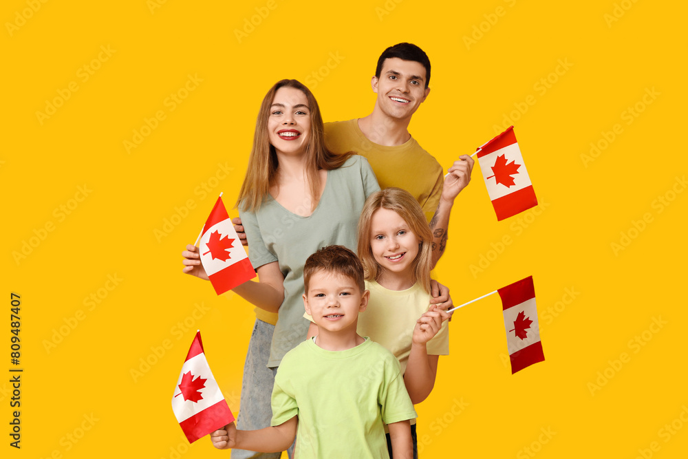 Beautiful family with flags of Canada on yellow background Beautiful family with flags of Canada on yellow background