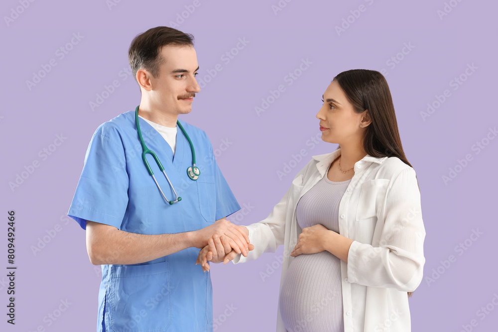 Young pregnant woman with doctor holding hands on lilac background Young pregnant woman with doctor holding hands on lilac background