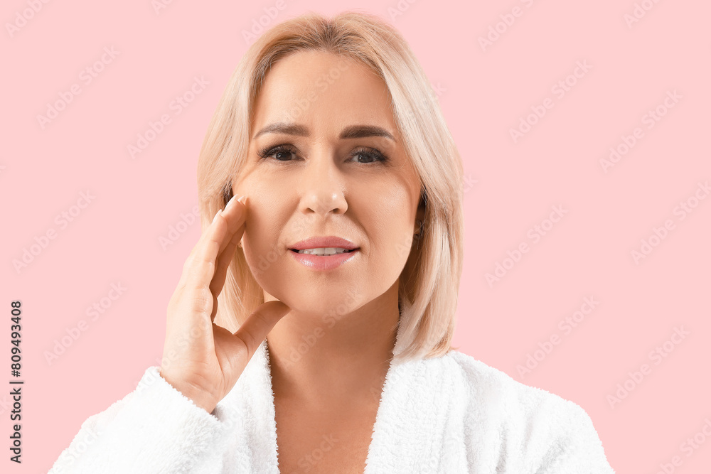 Beautiful mature happy woman in bathrobe with healthy skin on pink background Beautiful mature happy woman in bathrobe with healthy skin on pink background