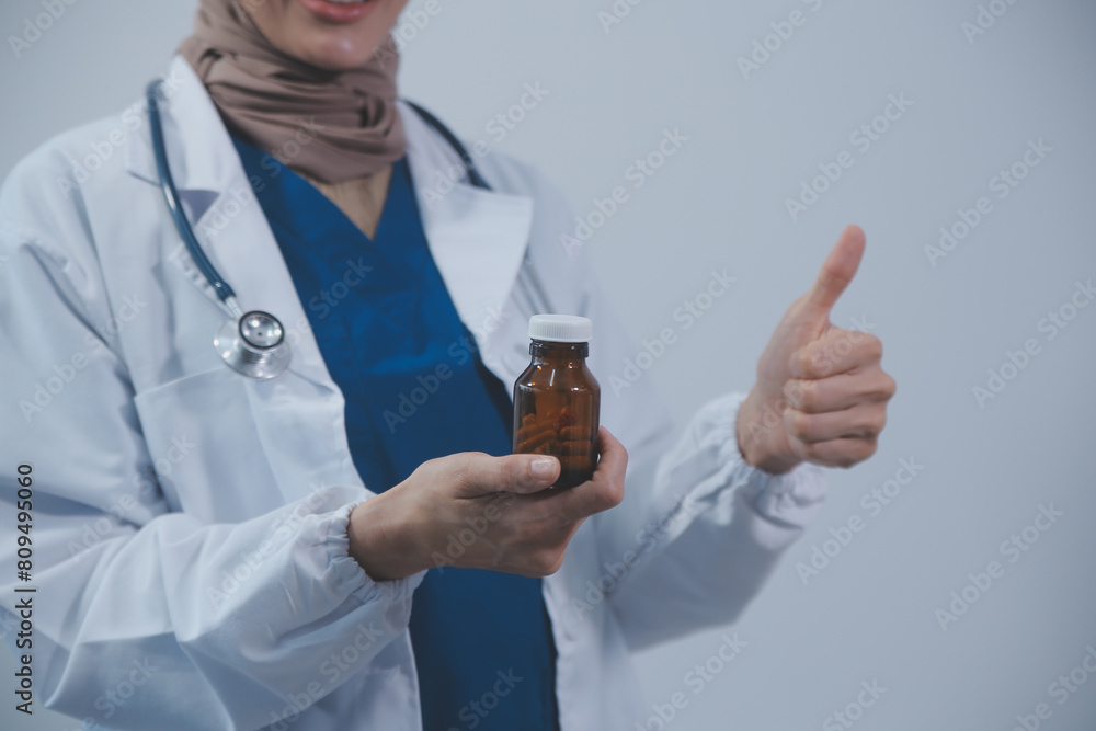 Southeast Asian medical doctor holding a bottle of pills, smiling isolated white background Southeast Asian medical doctor holding a bottle of pills, smiling isolated white background