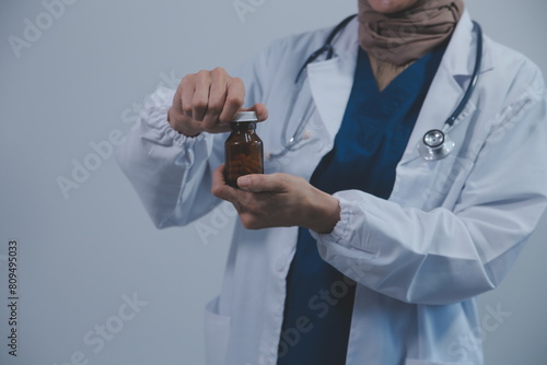 Southeast Asian medical doctor holding a bottle of pills, smiling isolated white background