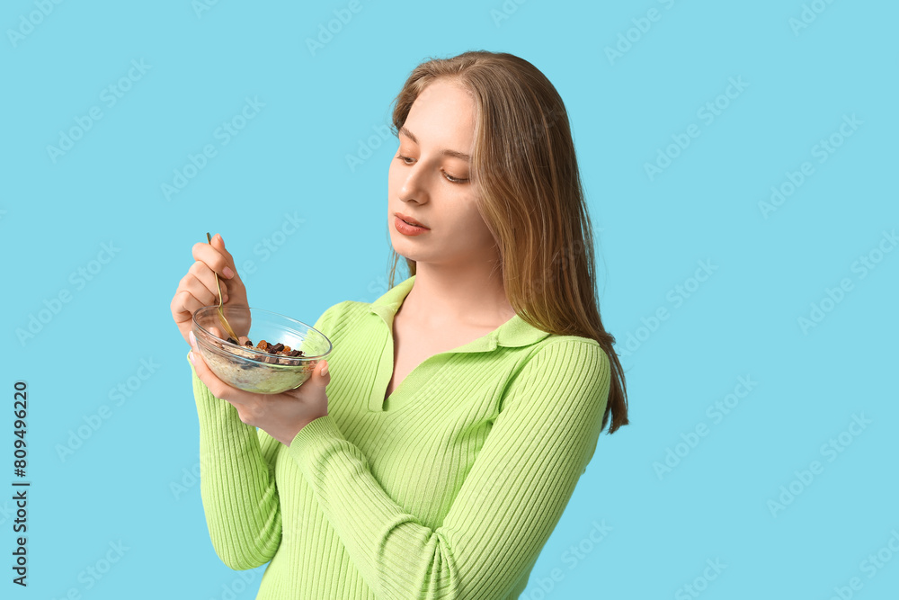 Young woman with bowl of healthy oatmeal on blue background Young woman with bowl of healthy oatmeal on blue background