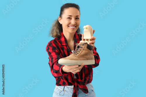 Female shoemaker repairing shoe with tree on blue background