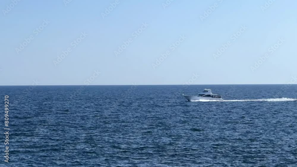 A lone boat speeds across the vast blue ocean under a clear sky A lone boat speeds across the vast blue ocean under a clear sky