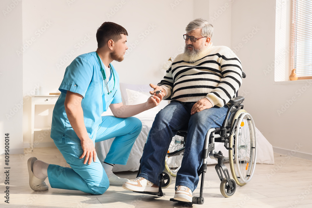Senior man in wheelchair with pulse oximeter and caregiver at home Senior man in wheelchair with pulse oximeter and caregiver at home