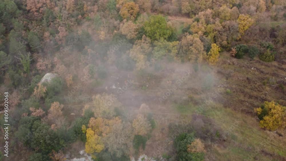 Osona's foggy landscape in autumn, showcasing colorful trees and rocky terrain, aerial view Osona's foggy landscape in autumn, showcasing colorful trees and rocky terrain, aerial view