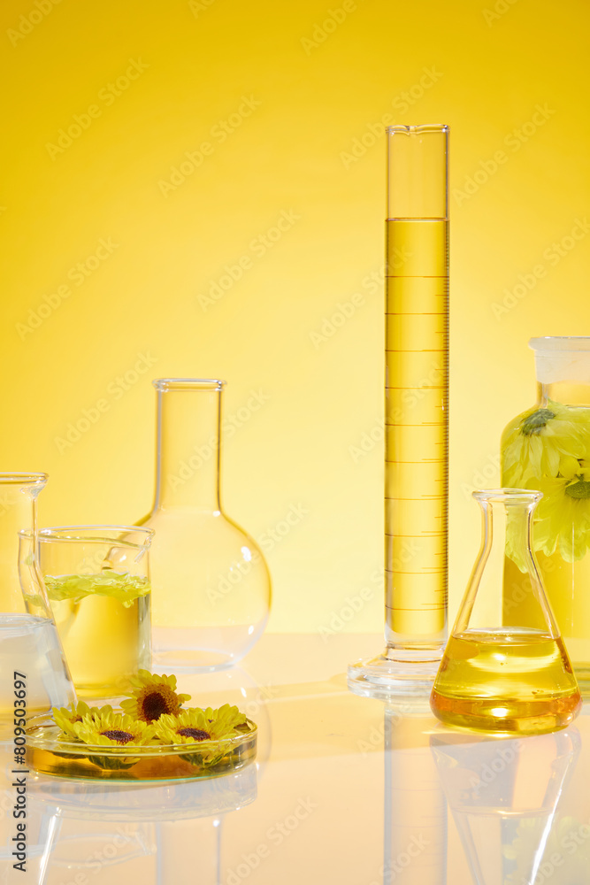 Frontal photo with plenty items of laboratory and calendula placed on white flat form over yellow background. Calendula has been used to treat a variety of skin conditions Frontal photo with plenty items of laboratory and calendula placed on white flat form over yellow background. Calendula has been used to treat a variety of skin conditions