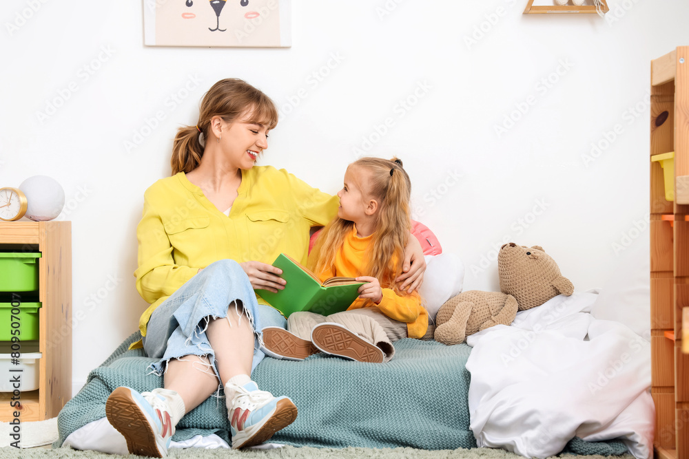 Nanny with little girl reading book in bedroom Nanny with little girl reading book in bedroom