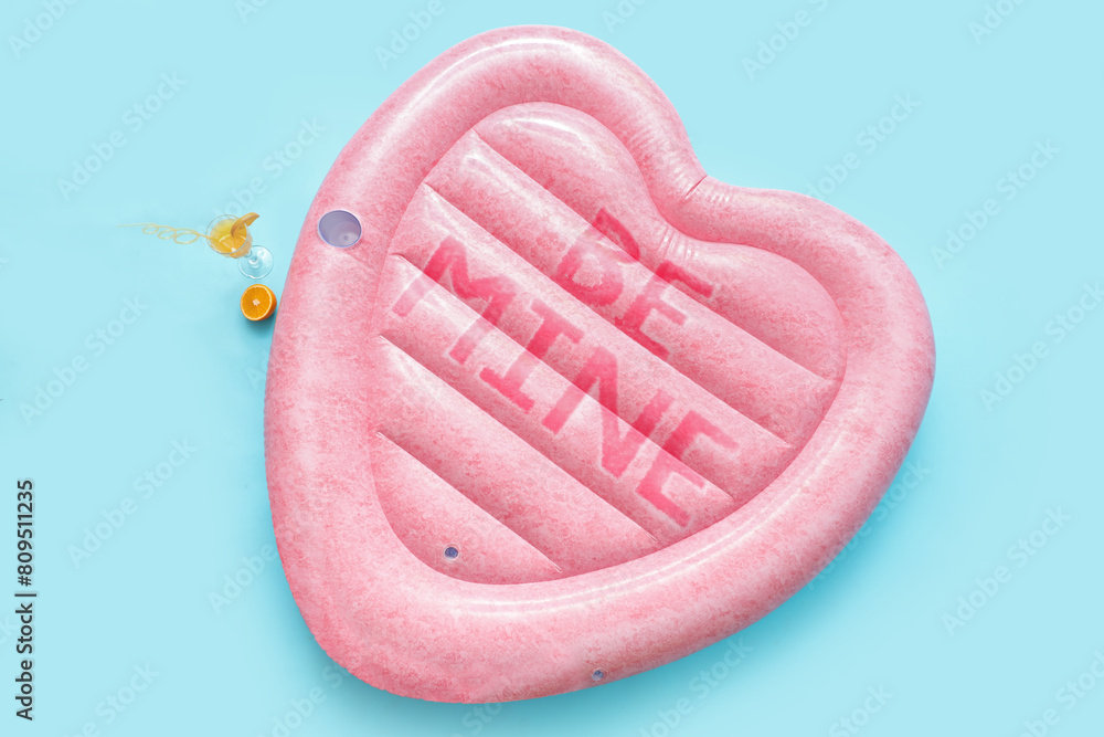 Inflatable mattress in shape of heart and cocktail on blue background Inflatable mattress in shape of heart and cocktail on blue background