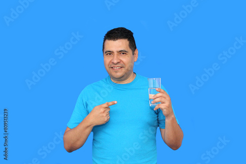 Dark-skinned Latino adult man shows his glass with still water to hydrate himself in hot weather