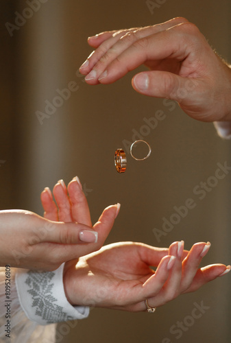 Hands of the bride and groom and levitating wedding rings
