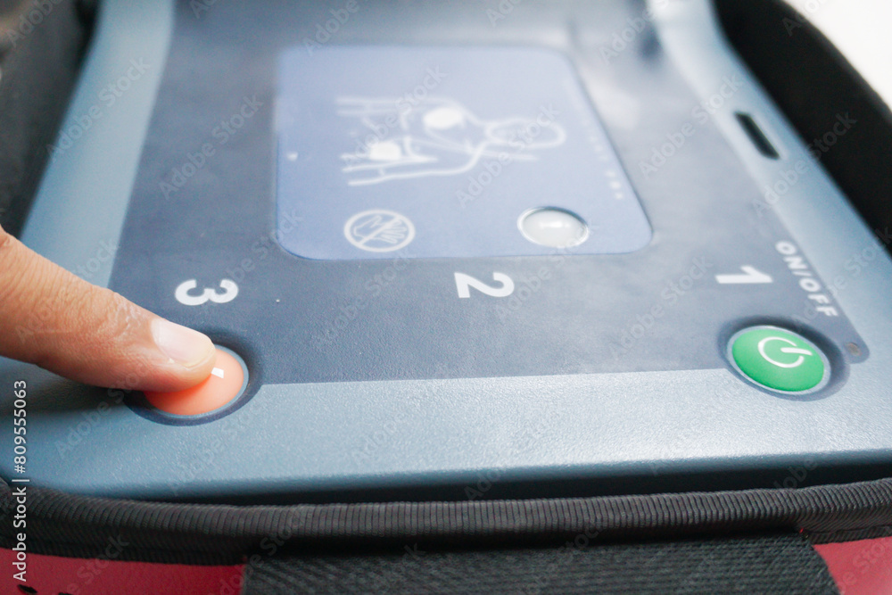 pressing the AED's shock button to deliver an electric shock to a heart attack patient pressing the AED's shock button to deliver an electric shock to a heart attack patient