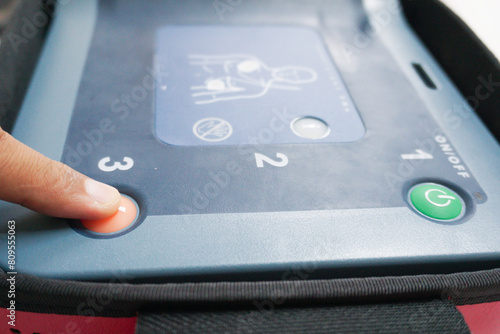 pressing the AED's shock button to deliver an electric shock to a heart attack patient