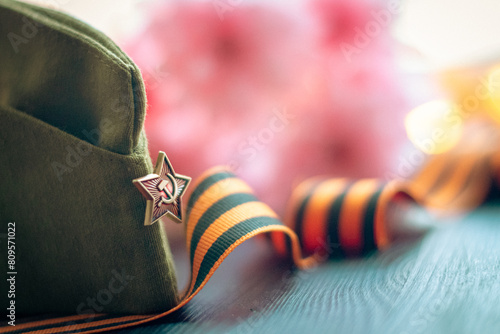 Soviet cap, St. George's ribbon on a background of flowers and glowing lights, symbols of the Victory Day of the Soviet people over fascism in World War II photo