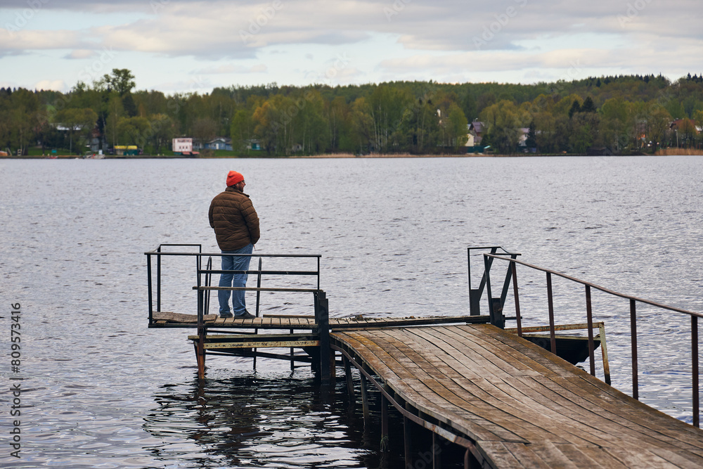 a man sits on a wooden pier on a river in the country