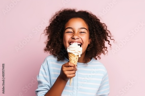 Dark-skinned African child eating ice cream in a cone and smiling happily on a pink background