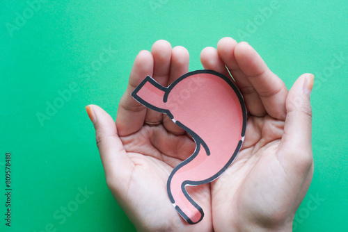 Fotografija Hand holding human stomach on green background