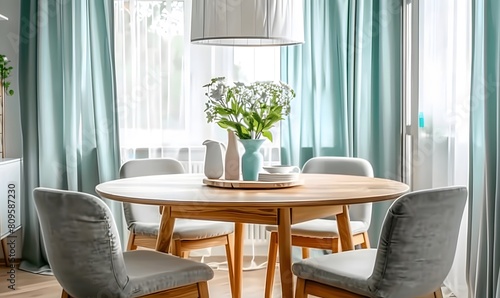 Round wooden table and fabric chairs against window dressed with turquoise curtains. Scandinavian home interior design of modern dining room.