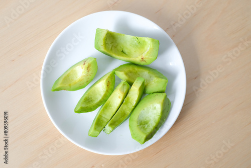 Avocado slice on a white plate and brown wooden table.