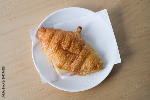 Ham cheese croissant on a white plate for breakfast.