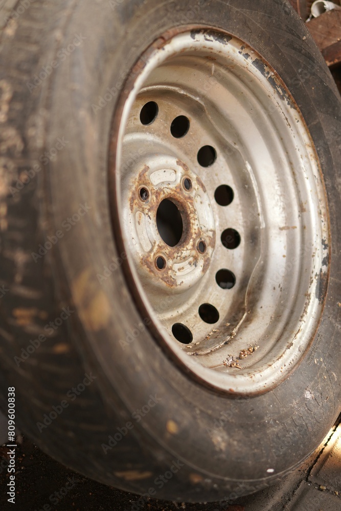A spare tire, along with its rim, kept for an extended period, showcasing resilience and readiness. A spare tire, along with its rim, kept for an extended period, showcasing resilience and readiness.