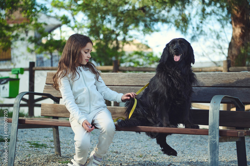 Little child nd her dog on the city bench in the nature outdoors. Cute child walking her dog on leash photo