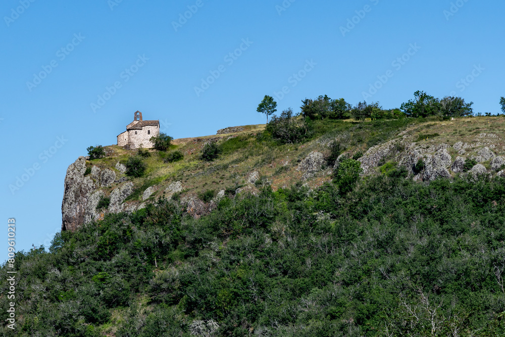 La chapelle Sainte Madeleine en haut de sa montagne dominant la vallée de Massiac dans le Cantal entourée de gros rochers par une belle journée d'été La chapelle Sainte Madeleine en haut de sa montagne dominant la vallée de Massiac dans le Cantal entourée de gros rochers par une belle journée d'été