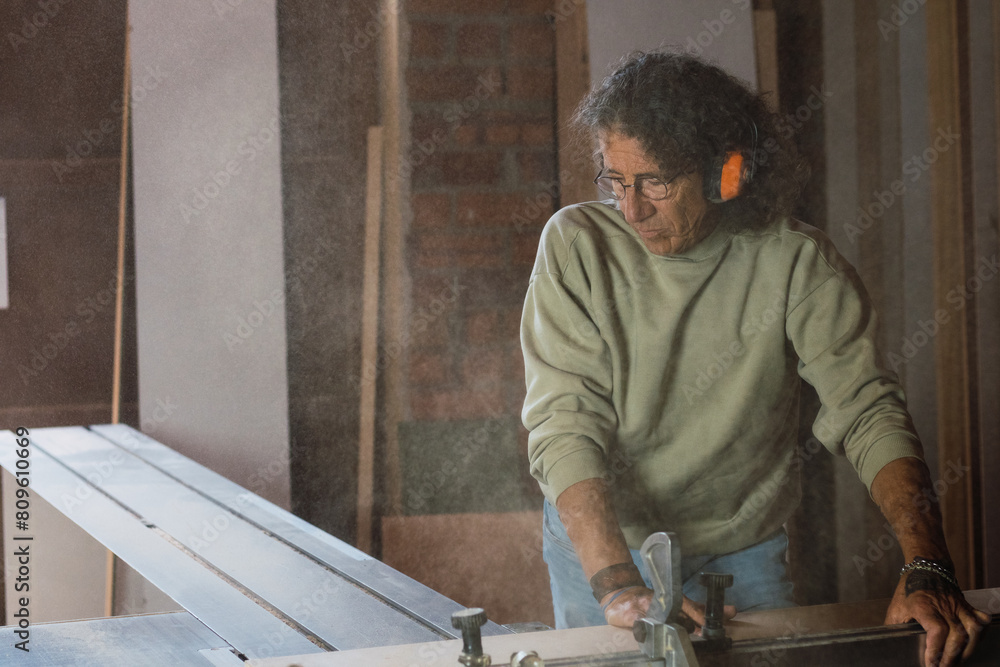 Carpenter working with electric planer on wooden plank in workshop. Craftsman makes own successful small business. Carpenter working with electric planer on wooden plank in workshop. Craftsman makes own successful small business.