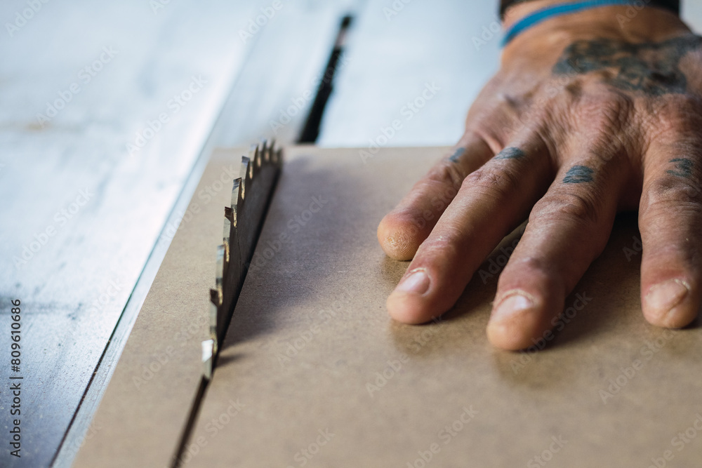 Carpenter cutting a wooden plank with a carpentry machine. Carpenter cutting a wooden plank with a carpentry machine.